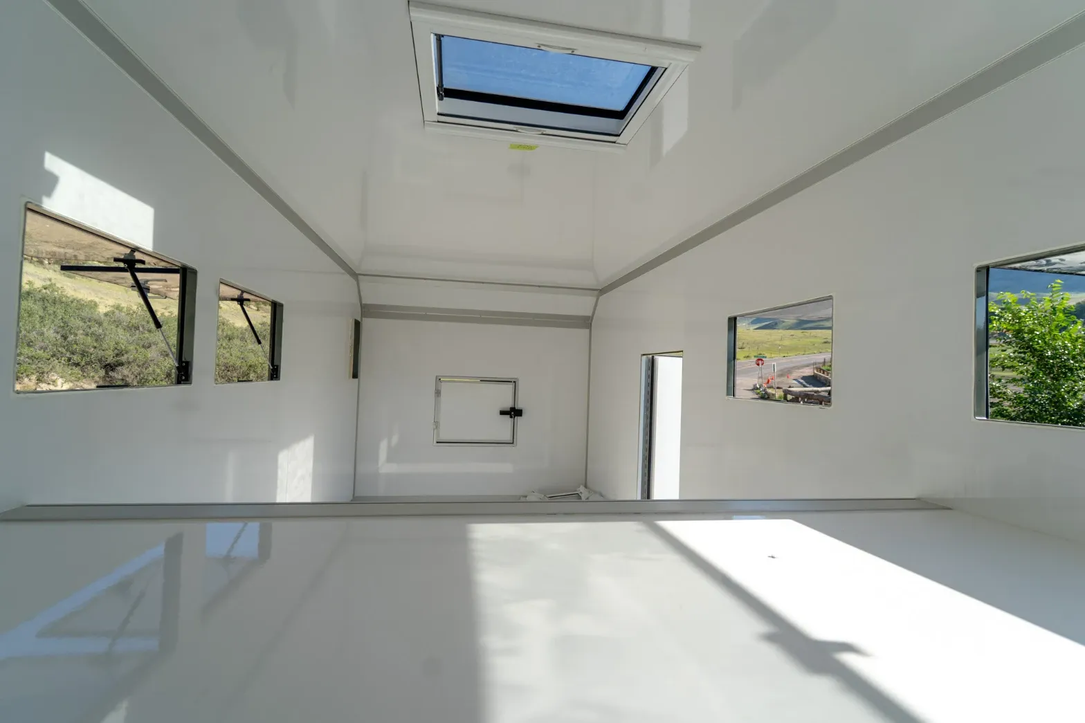 Interior of an empty white composite body with a roof skylight and awning windows
