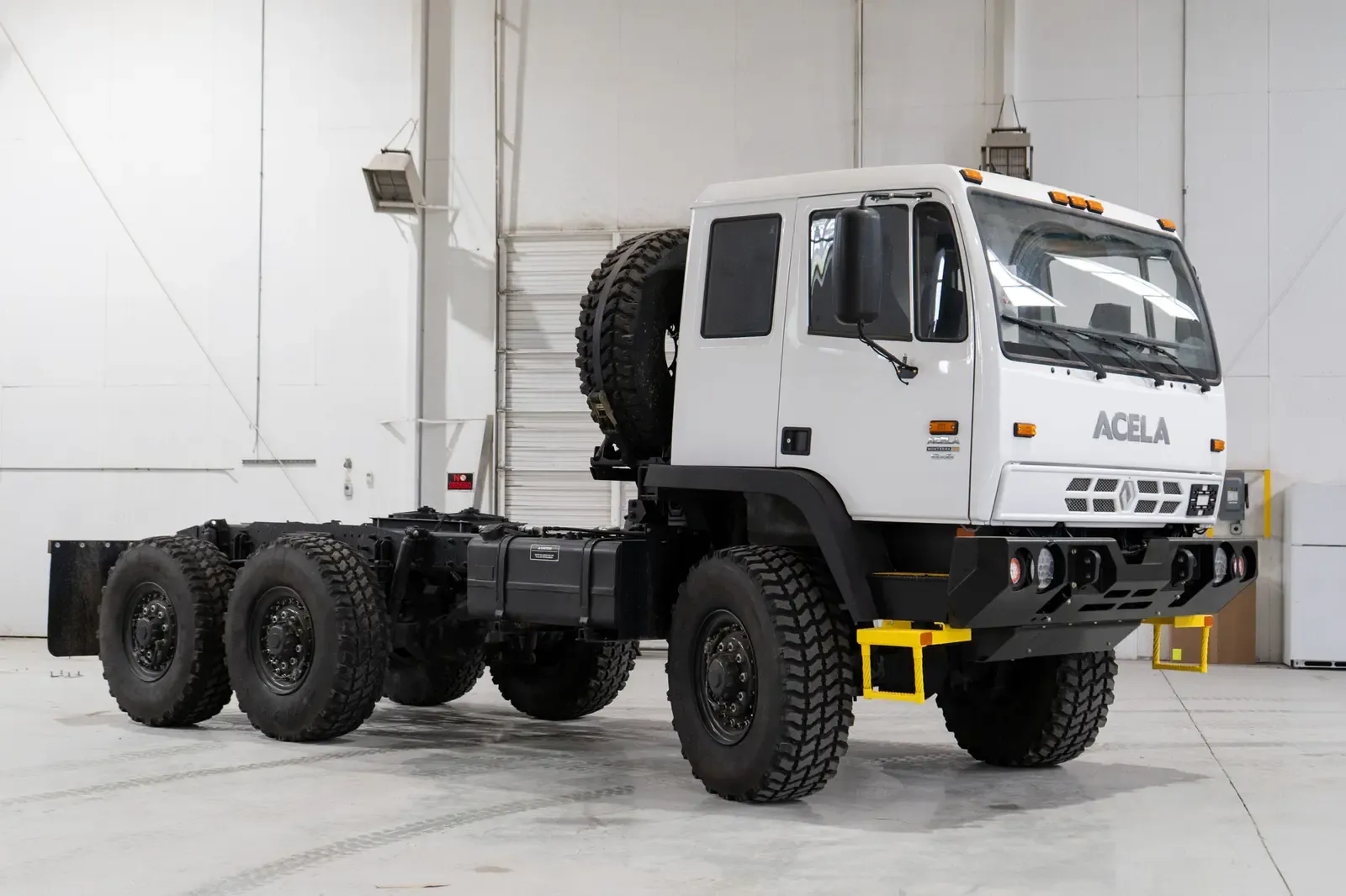 White Acela Monterra 6x6 cab-chassis, side profile showing the full six-wheel-drive chassis