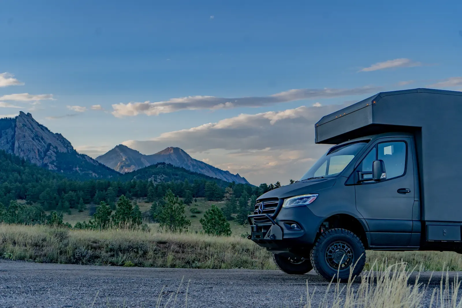 Matte-olive FV-170 demo composite camper on a Mercedes-Benz Sprinter 170, front three-quarter view with mountains behind
