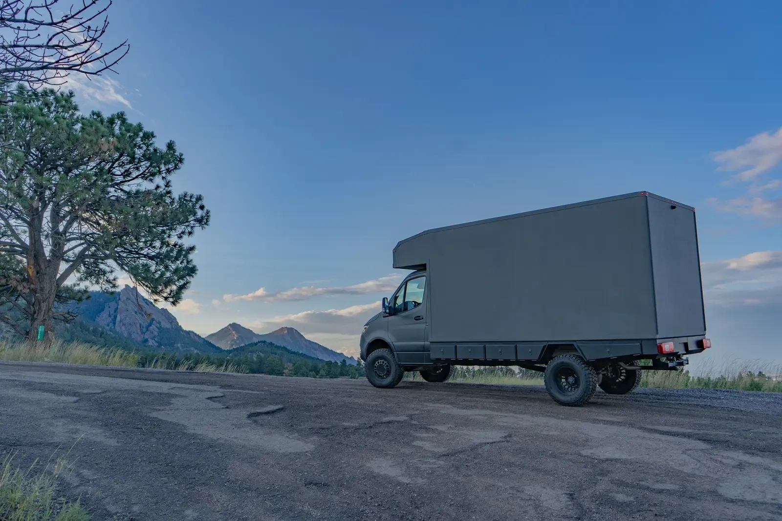 Matte-olive FV-170 demo composite camper on a Mercedes-Benz Sprinter 170, side-rear view on a gravel road at dusk