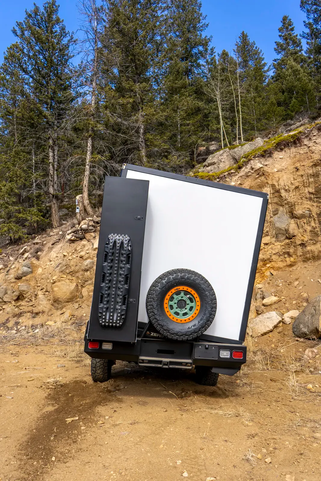 White E-158 composite box camper on a Ford E-Series 4x4, rear three-quarter view showing the spare tire on the rear door