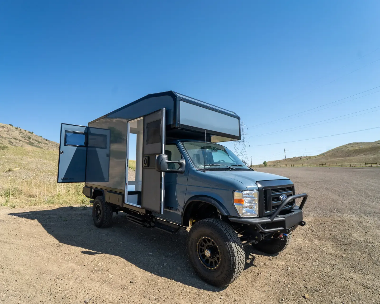 Ford E-Series E-158S 4x4 composite camper with the entry door open, front three-quarter view