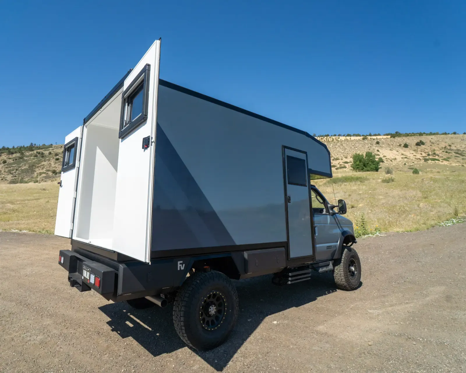 Cavalry Blue and white Ford E-Series E-158S 4x4 composite camper, rear three-quarter view showing the full-height rear doors