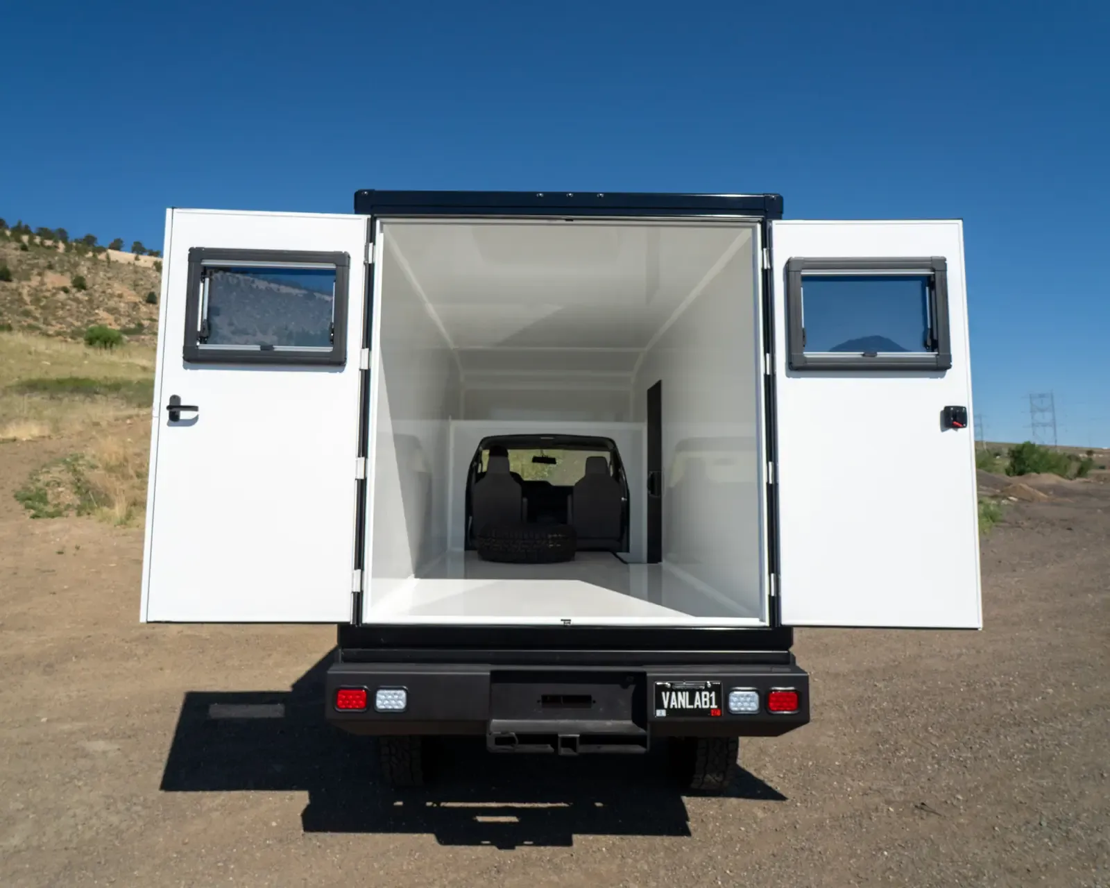 Inside the composite body with both full-height rear doors open, showing the bright white interior and a view through to the cab