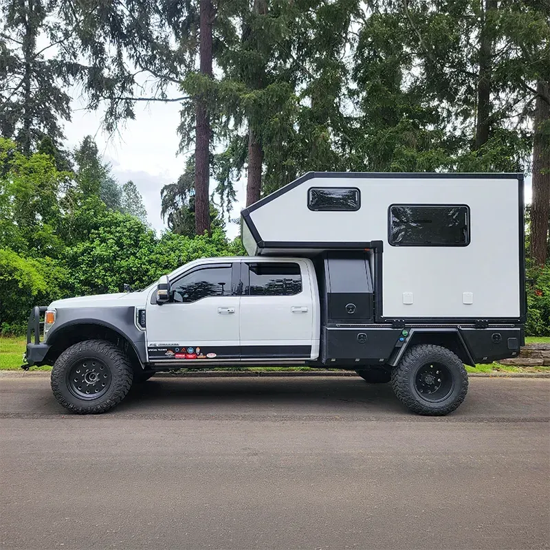 A composite flatbed camper on a dually Super Duty truck on a forest road, side view
