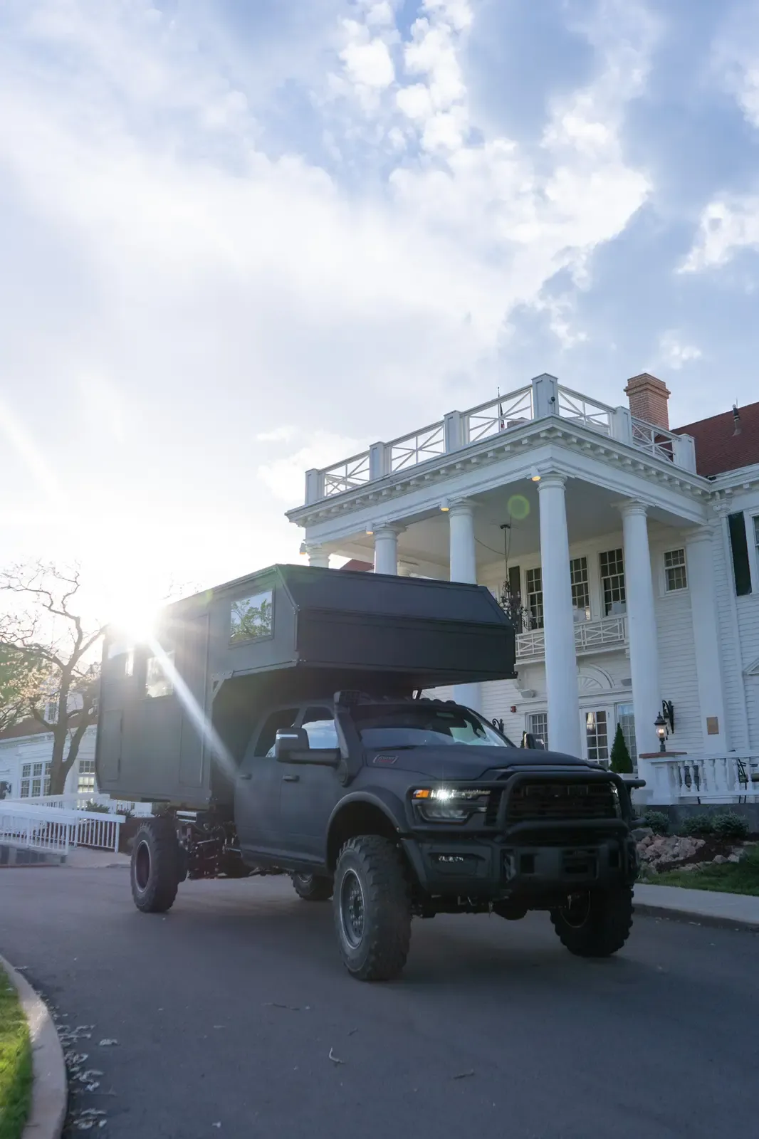Black composite flatbed camper on a Ram 5500 cabover parked on a driveway in evening light