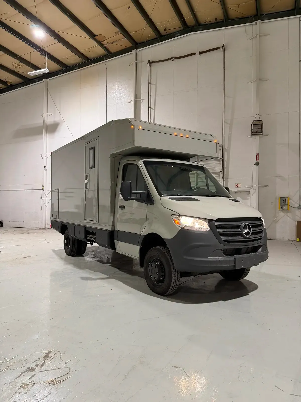 Stone Gray Mercedes-Benz Sprinter 170 with a Foundation composite camper body, front three-quarter view in the build shop