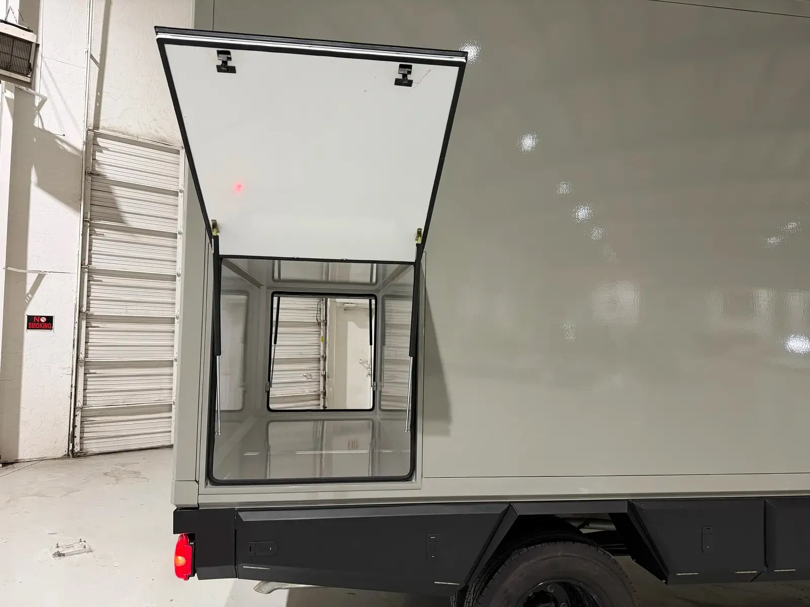 Stone Gray Mercedes-Benz Sprinter with the rear doors open, showing the bright composite interior