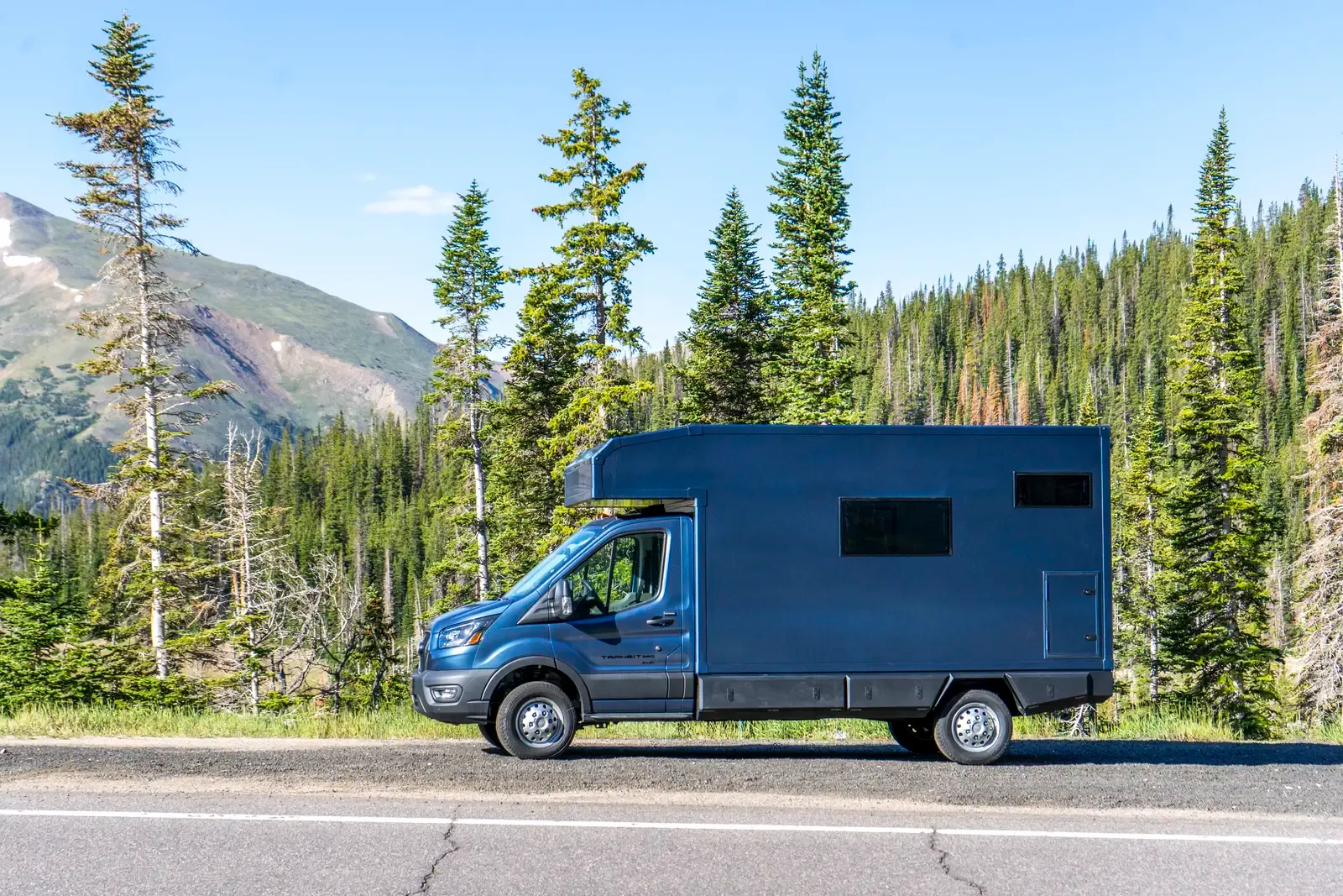Blue composite box camper on a Ford Transit 156, rear three-quarter view showing the tall composite body