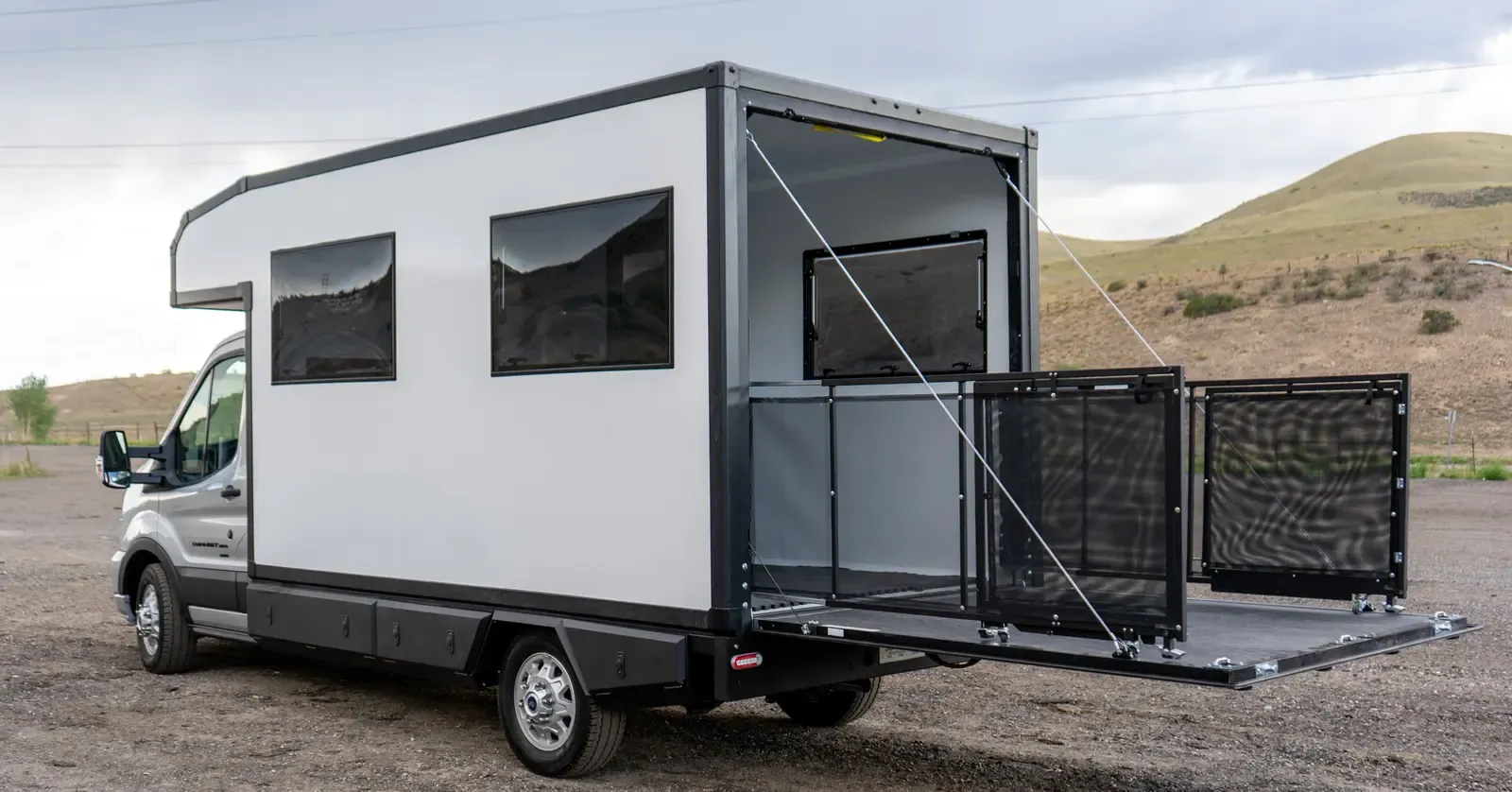Foundation Vehicles RampDeck body on a Ford Transit 156 opened into a railed patio deck with mesh side panels, side view
